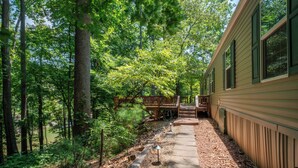 A cabin with a deck overlooking a forested area and a small stream. - Dragonfly Cove | Private Dock! (Mooresville)