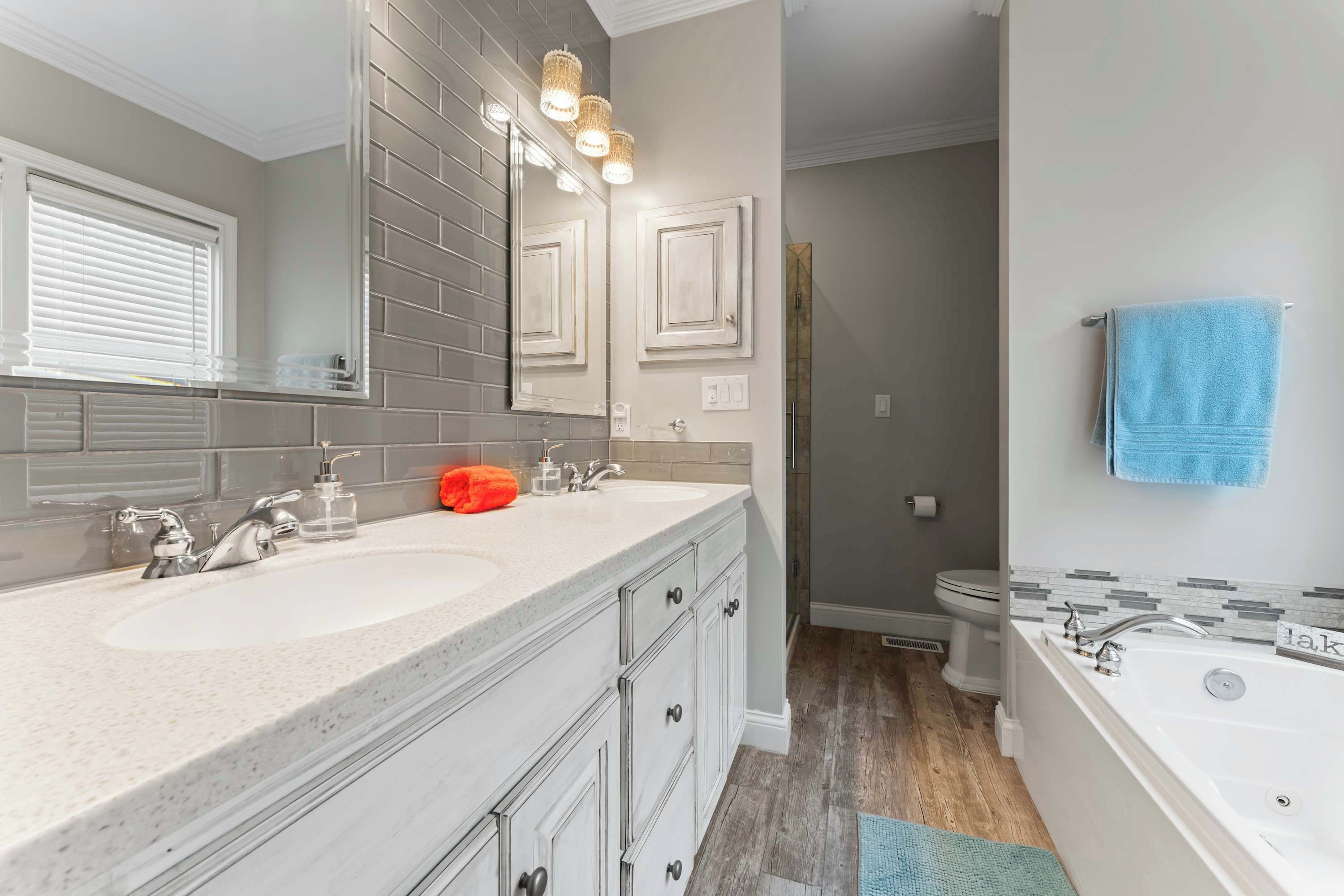 A bathroom with two sinks, a large mirror, a bathtub, and a shower area.