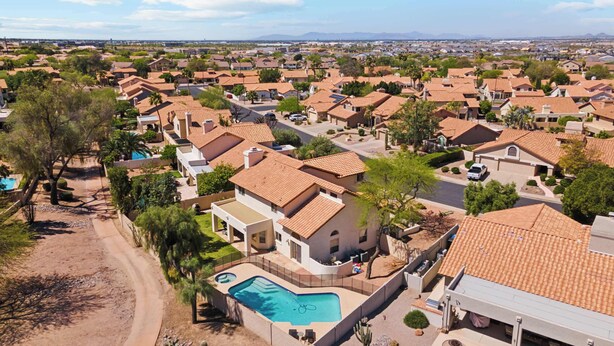 A residential area with houses featuring red-tiled roofs, a swimming pool, and a clear view of the surrounding landscape.