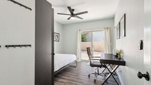 A compact room with a bed, a desk, and a ceiling fan.