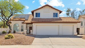 A two-story house with a garage, solar panels, and cacti in the front yard.