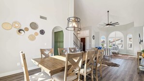 Un'area pranzo con un tavolo e sedie in legno, una ventola a soffitto e una scala che conduce a un altro livello.