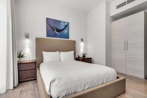Ein modernes Schlafzimmer mit einem großen Bett, Nachttischen, einem Kleiderschrank und einem Walbild an der Wand.