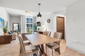 A modern living room with a dining area, large windows, and a view of the outdoors. - BEACHFRONT CONDO WITH ROOFTOP POOL (Hollywood)