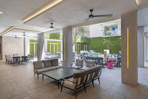 An outdoor patio area with seating arrangements, including sofas and tables, and a visible pool in the background. - BEACHFRONT CONDO WITH ROOFTOP POOL (Hollywood)