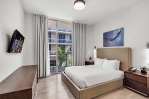 A modern hotel room with a large bed, a bedside table with a phone, a small plant, and a painting of a whale on the wall. - Hollywood Beach Escape | Rooftop Pool & Spa (Hollywood)