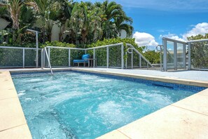 A swimming pool with a blue tiled edge, surrounded by a white metal fence, and a blue chair. - Hollywood Beach Escape | Rooftop Pool & Spa (Hollywood)
