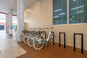 A clean, modern indoor space with bicycles parked against a wall, a large window, and a tiled floor. - BEACHFRONT CONDO WITH ROOFTOP POOL (Hollywood)
