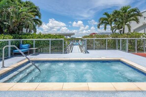A swimming pool with a clear view of the water, surrounded by palm trees and a covered seating area.