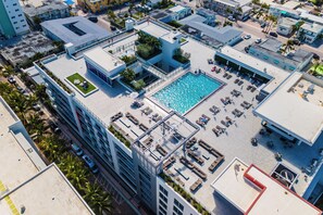 An aerial view of a hotel with a rooftop pool, multiple balconies, and a mix of modern and traditional architecture.