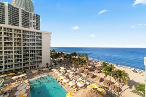 A hotel with a pool area, beach, and ocean view.