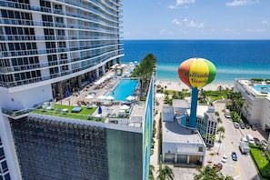 A high-rise hotel with a swimming pool, beach view, and a colorful beach ball sign.