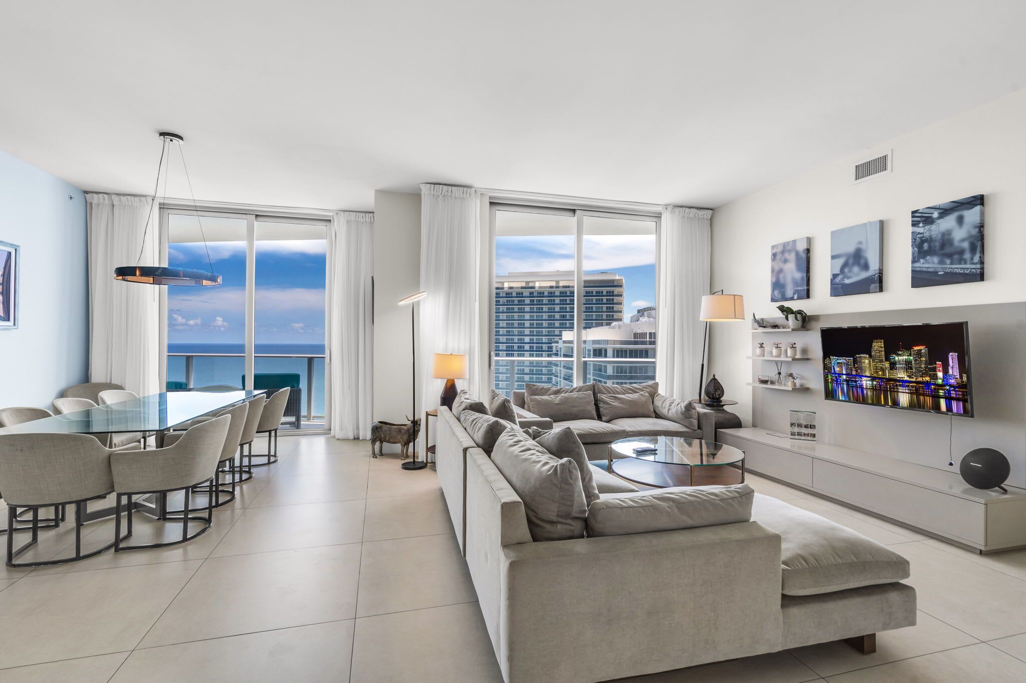 A modern living room with a glass dining table, sofas, and a TV.