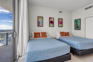 Une chambre d'hôtel avec deux lits, une vue sur la ville et des œuvres d'art aux murs.