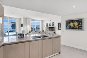 Una cocina moderna con una isla grande, un comedor con vistas y una sala de estar con sofá y mesa de centro.