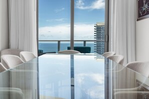 A modern conference room with a glass table, white chairs, and a view of the ocean and a high-rise building. - Stunning  Penthouse  Resort Amenities  12 people (Hollywood)