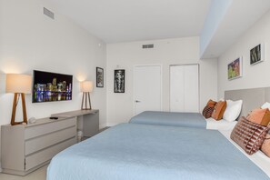 A hotel room with two beds, a TV, a desk, and a dresser. - LYFE Resort | 39th Floor Oceanview Penthouse (Hollywood)