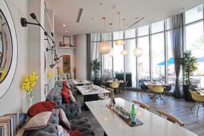 Un área de comedor moderna con una larga mesa común, asientos acolchados e iluminación colgante.