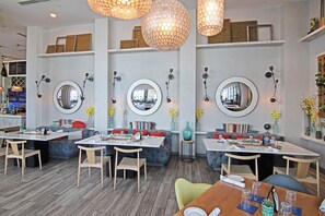 Un comedor moderno con espejos redondos, mobiliario de madera e iluminación colgante.