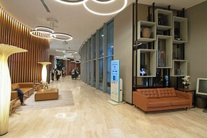 Un hall d’entrée moderne doté d’un espace salon, d’un kiosque d’information numérique et d’une grande fenêtre.