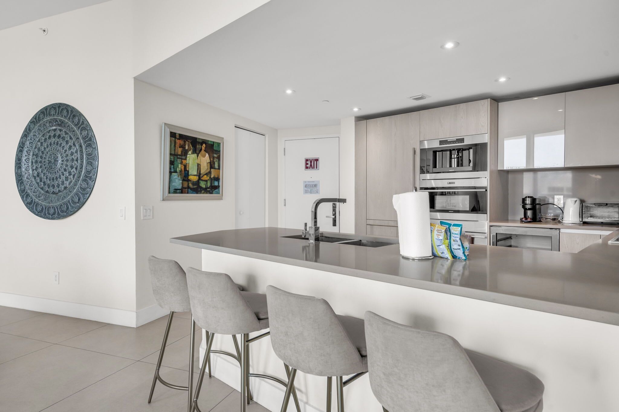 Een moderne keuken met een centraal eiland, barstoelen en een magnetron.