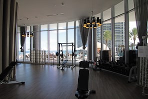 A gym with large windows, exercise equipment, and a view of the city.