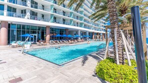 Un hotel con zona de piscina, varios balcones y palmeras.
