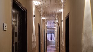 Un pasillo largo y estrecho con suelo de madera y varias puertas a ambos lados.