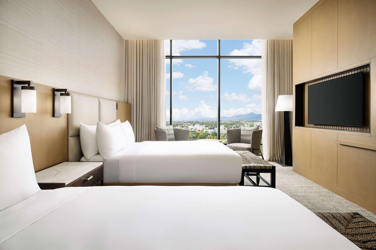 Une chambre d’hôtel avec un grand lit, une télévision, un bureau et une vue sur la ville.