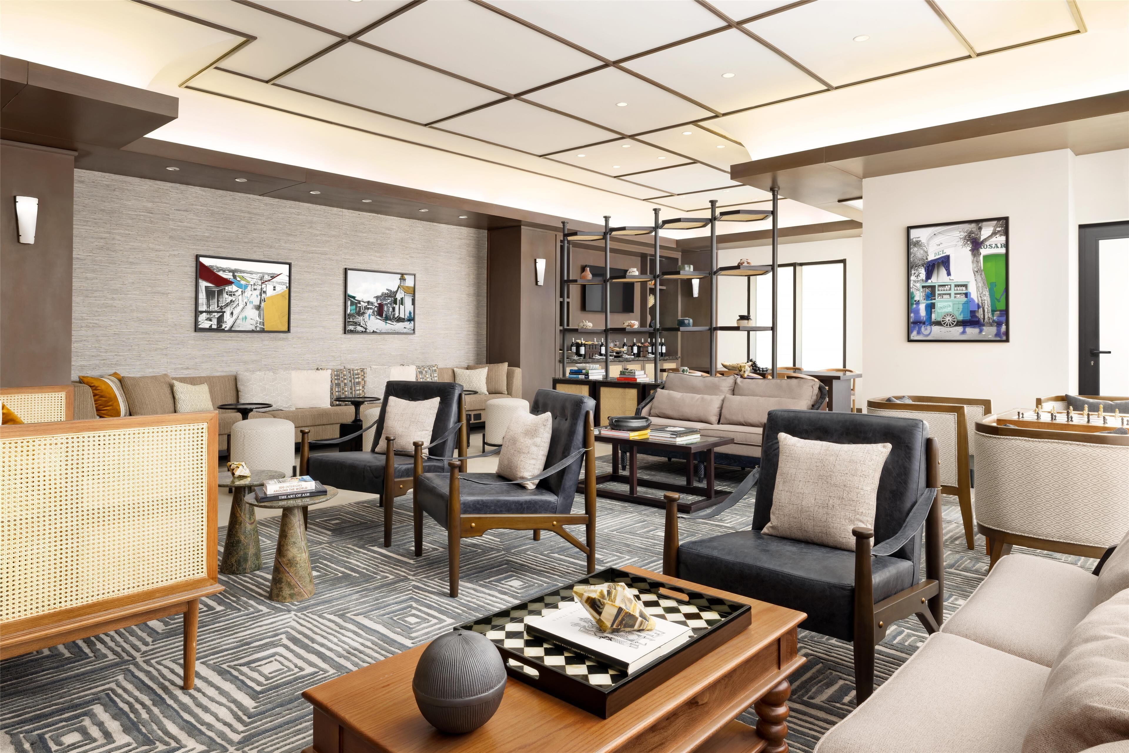 A modern living room with a sofa, armchairs, a coffee table, and a bookshelf.