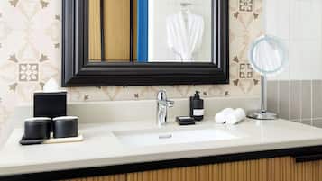 A bathroom with a large mirror, a sink, and two black containers on the counter.