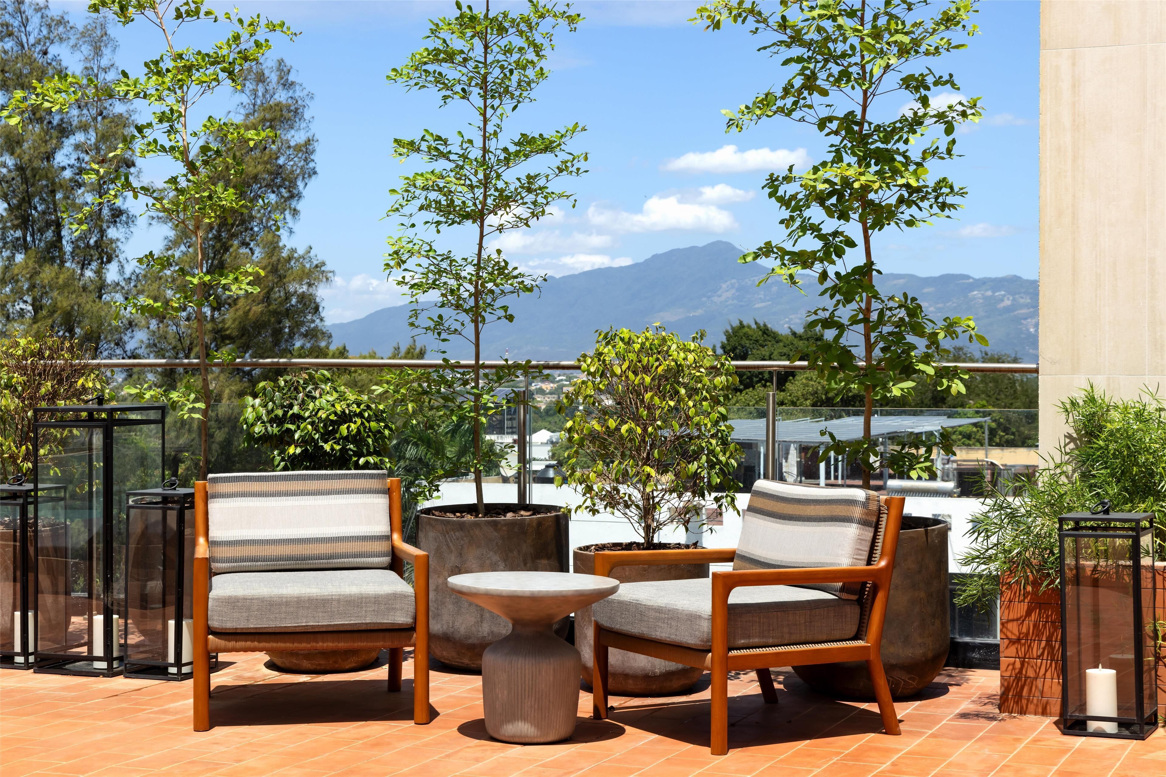 A terrace with outdoor furniture, potted plants, and a view of mountains.