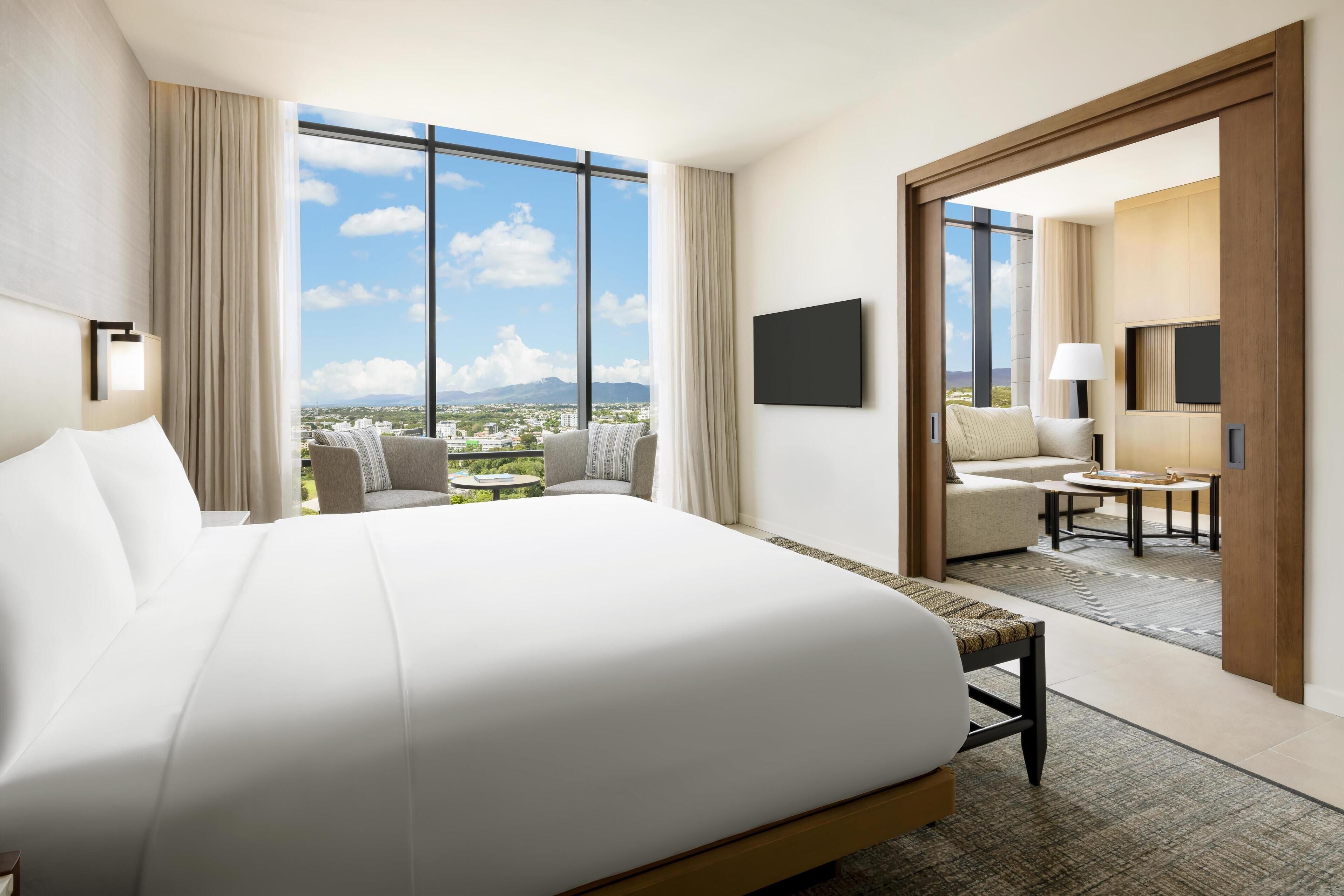 A modern hotel room with a large bed, a seating area with a view, and a television.
