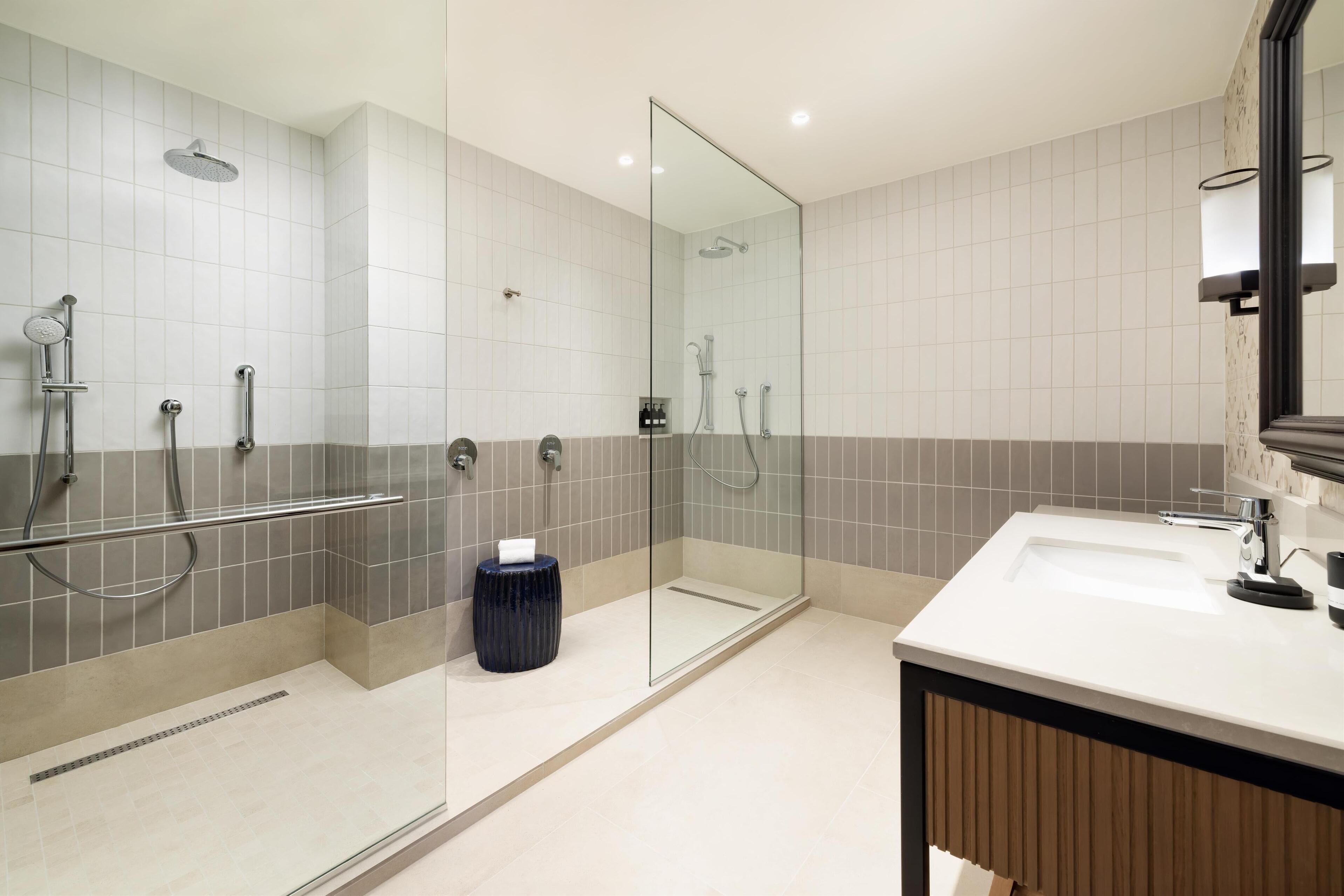 Un baño moderno con cabina de ducha de vidrio, un lavamanos blanco y un espejo.