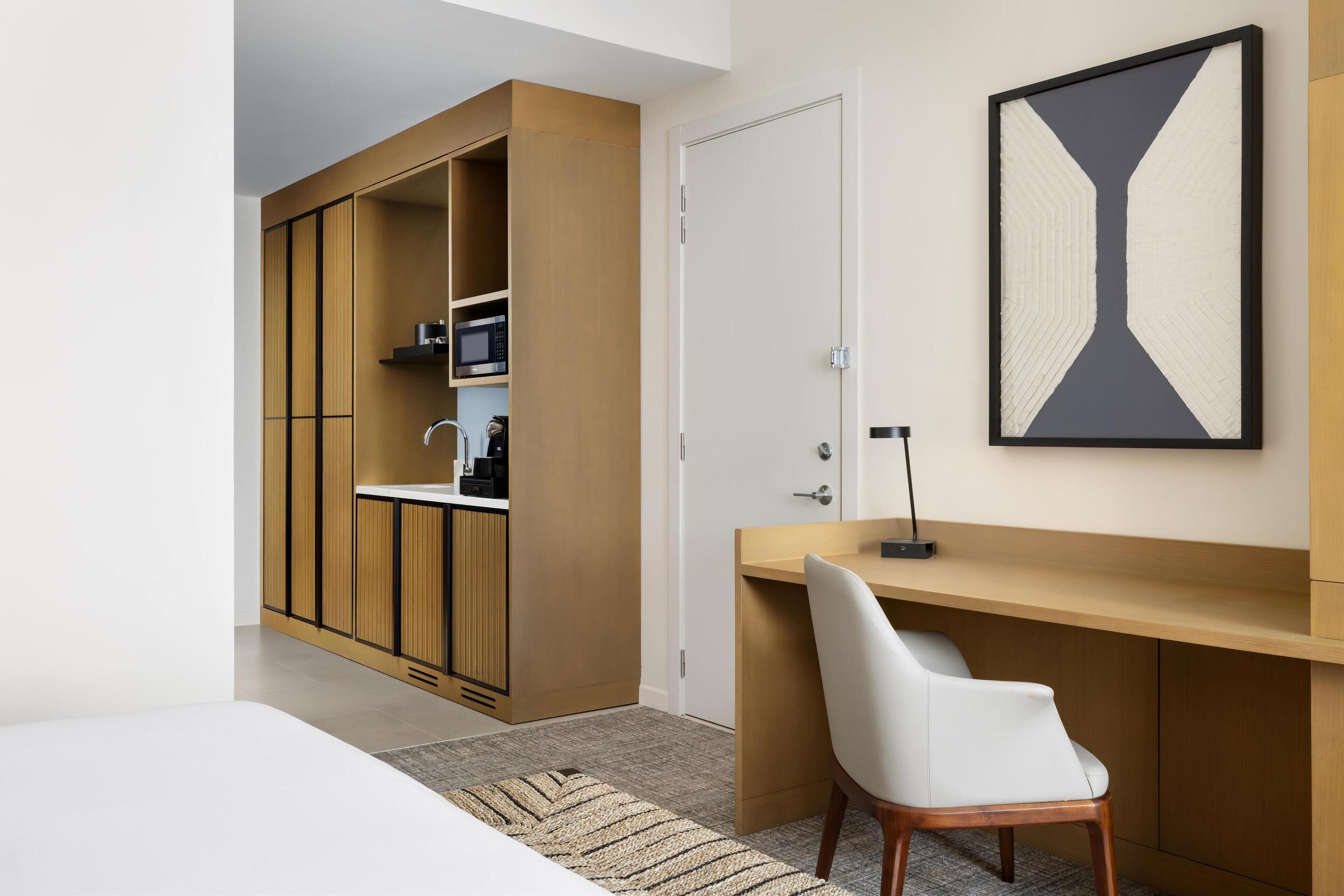A modern bedroom with a built-in wardrobe, a desk, and a large abstract painting.