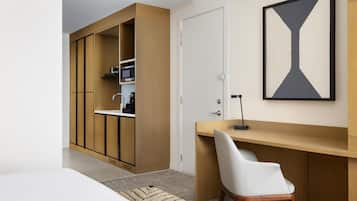 A modern bedroom with a built-in wardrobe, a desk, and a large abstract painting.