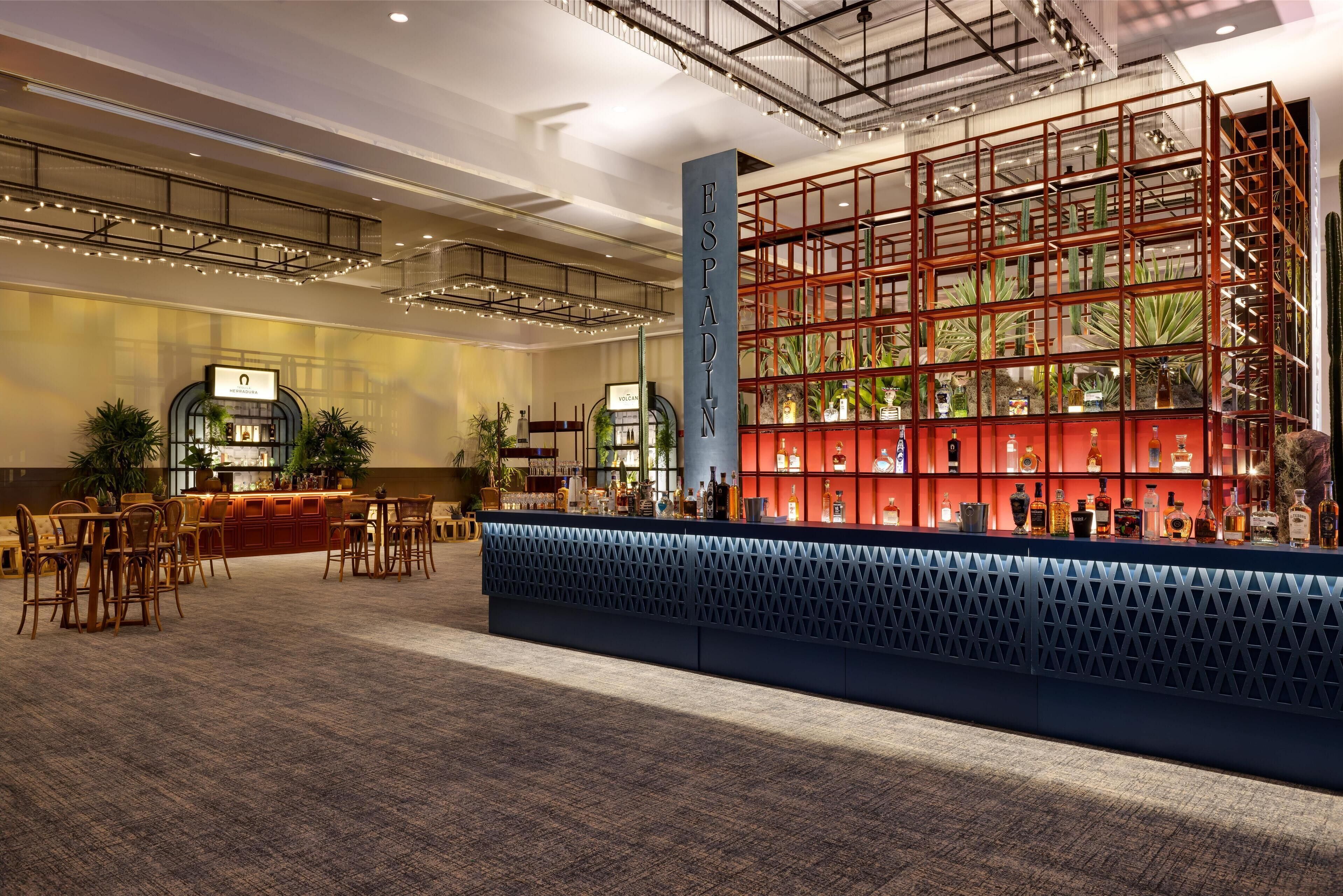 Een ruime lobby met een receptiebalie, zithoek en een grote rode en glazen constructie.