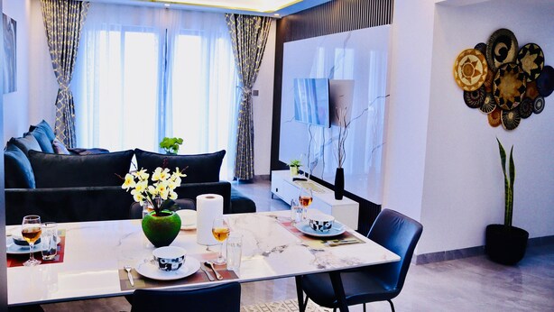 A modern living room with a sofa, dining table, and decorative wall art. - spacious 3 bedroom in kilimani gym&pool (Nairobi)