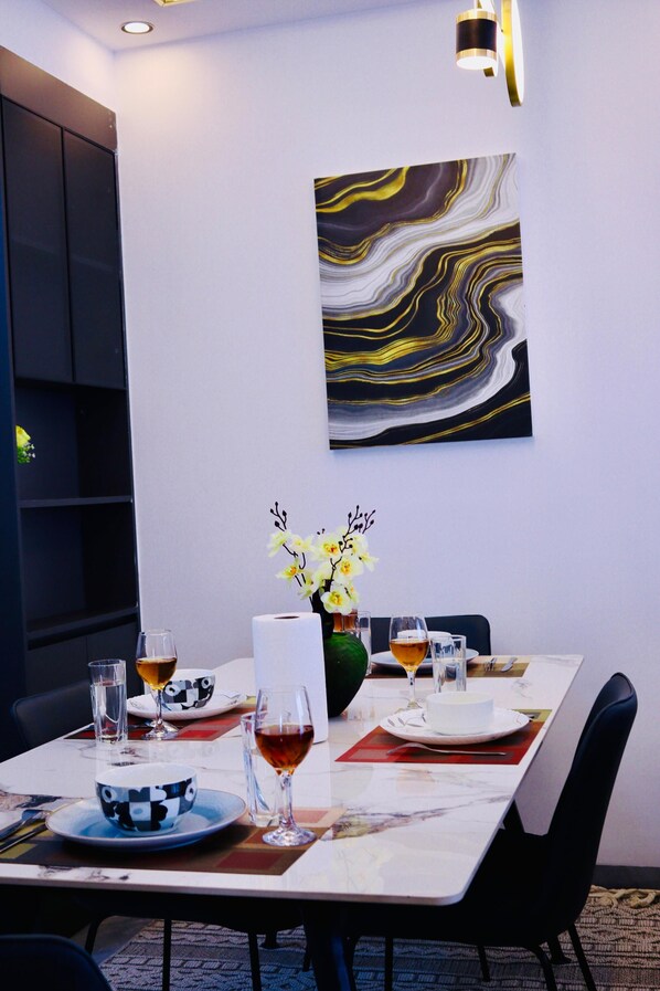 Ein Essbereich mit Tisch für zwei Personen, inklusive Blumenvase, Tellern und Gläsern.