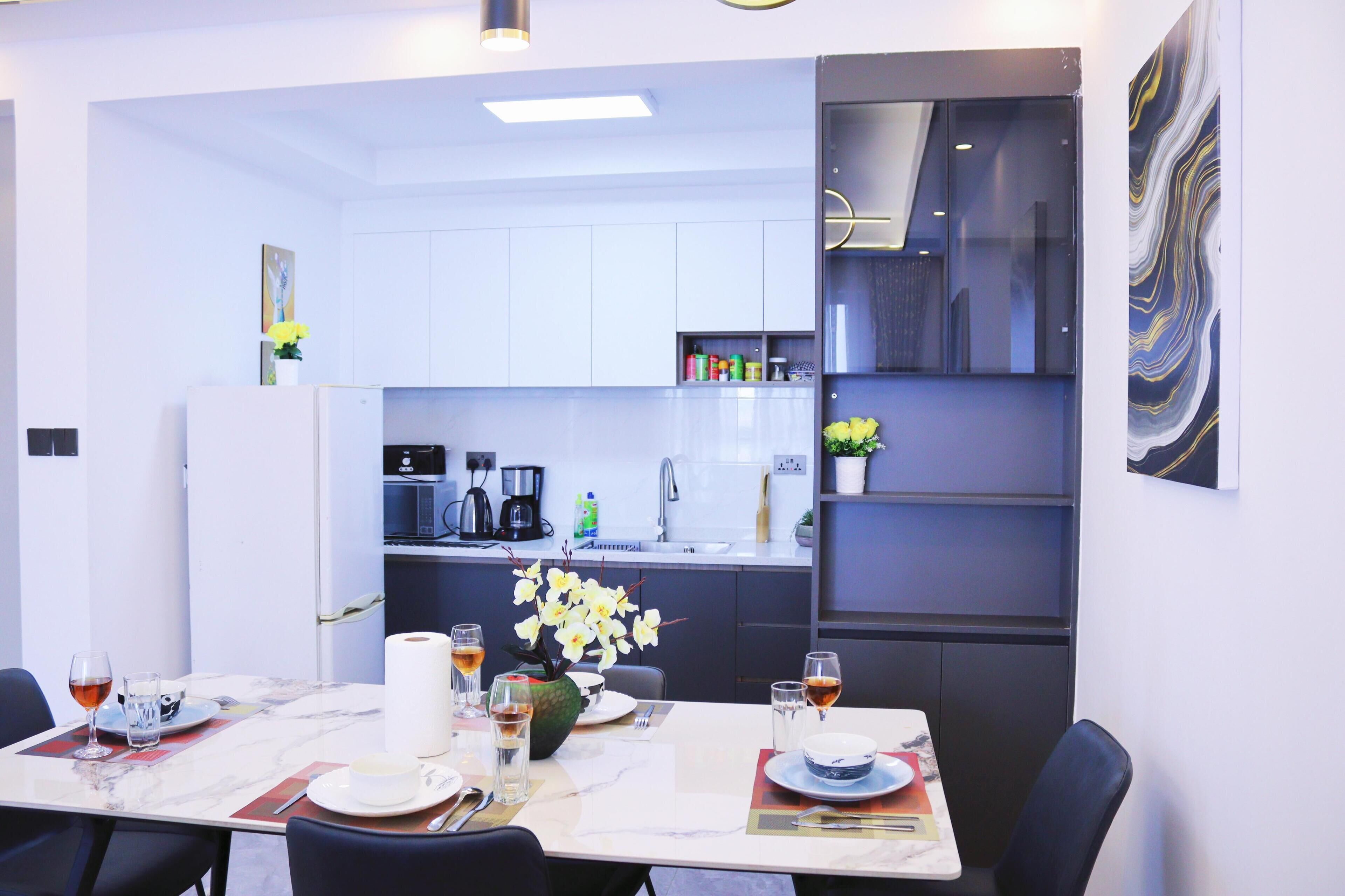 Un comedor moderno con una mesa de mármol, sillas y vista a la cocina.