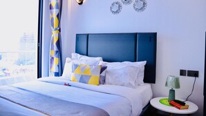 A hotel room with a bed, a round side table with a lamp, and decorative wall mirrors. - spacious 3 bedroom in kilimani gym&pool (Nairobi)