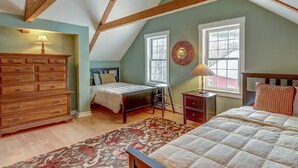 A bedroom with a sloped ceiling, a wooden dresser, two beds, a desk, and a window with a view. - Charming 3-bedroom house in marvelous Moretown (Moretown)