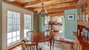 A spacious dining area with a wooden table and chairs, a chandelier, and a view of the kitchen in the background. - Charming 3-bedroom house in marvelous Moretown (Moretown)