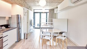A modern kitchen with a dining area, including a white table and chairs, a built-in oven, and a stainless steel refrigerator. - BabelUP (Buenos Aires)