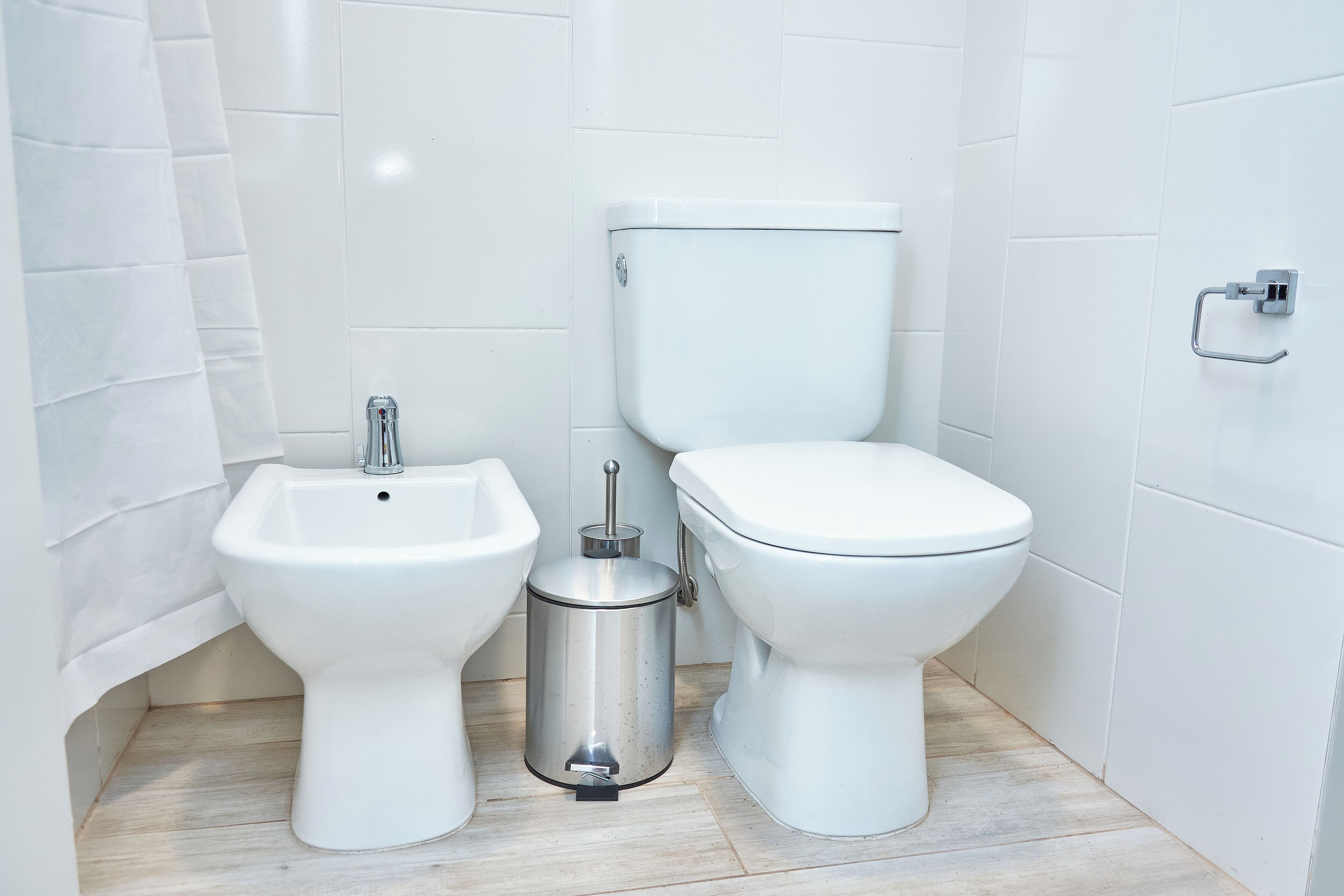 Une salle de bain équipée d’un bidet, de toilettes et d’une poubelle.