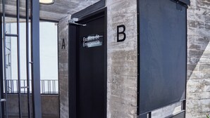 An emergency exit door labeled "Escalera de Emergencia" with a metal handle and a black door. - BabelUP (Buenos Aires)
