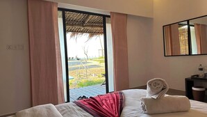 Une chambre d’hôtel avec un lit, un miroir, une table de chevet et une vue sur un jardin, accessible par une porte coulissante.