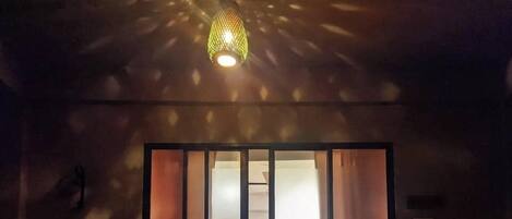 Una habitación con un ventanal grande, una cama y una lámpara colgante.