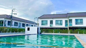 Une piscine à l’eau d’un bleu cristallin, entourée d’un bâtiment blanc doté de grandes fenêtres et d’un toit plat.