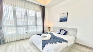 Une chambre à coucher moderne avec un grand lit, une table de chevet, une lampe et une œuvre d’art représentant un paysage urbain accrochée au mur.